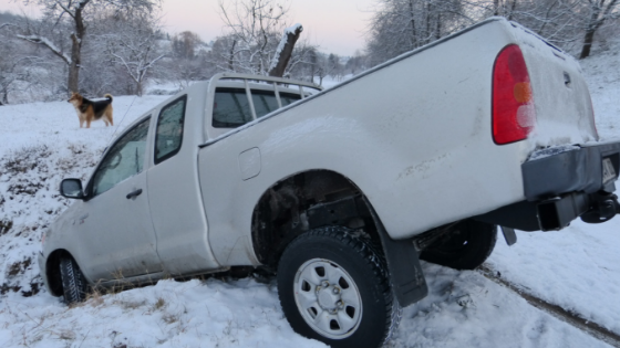 A white pickup truck stuck in a snowy ditch