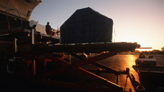 ground crew working on a plane at sunrise