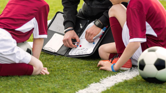 coach with soccer players drawing up a play