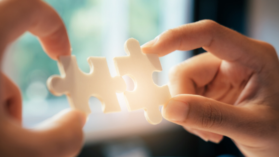 Two people connecting two puzzle pieces 